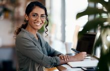 Woman holding a pen and smiling at the camera.
